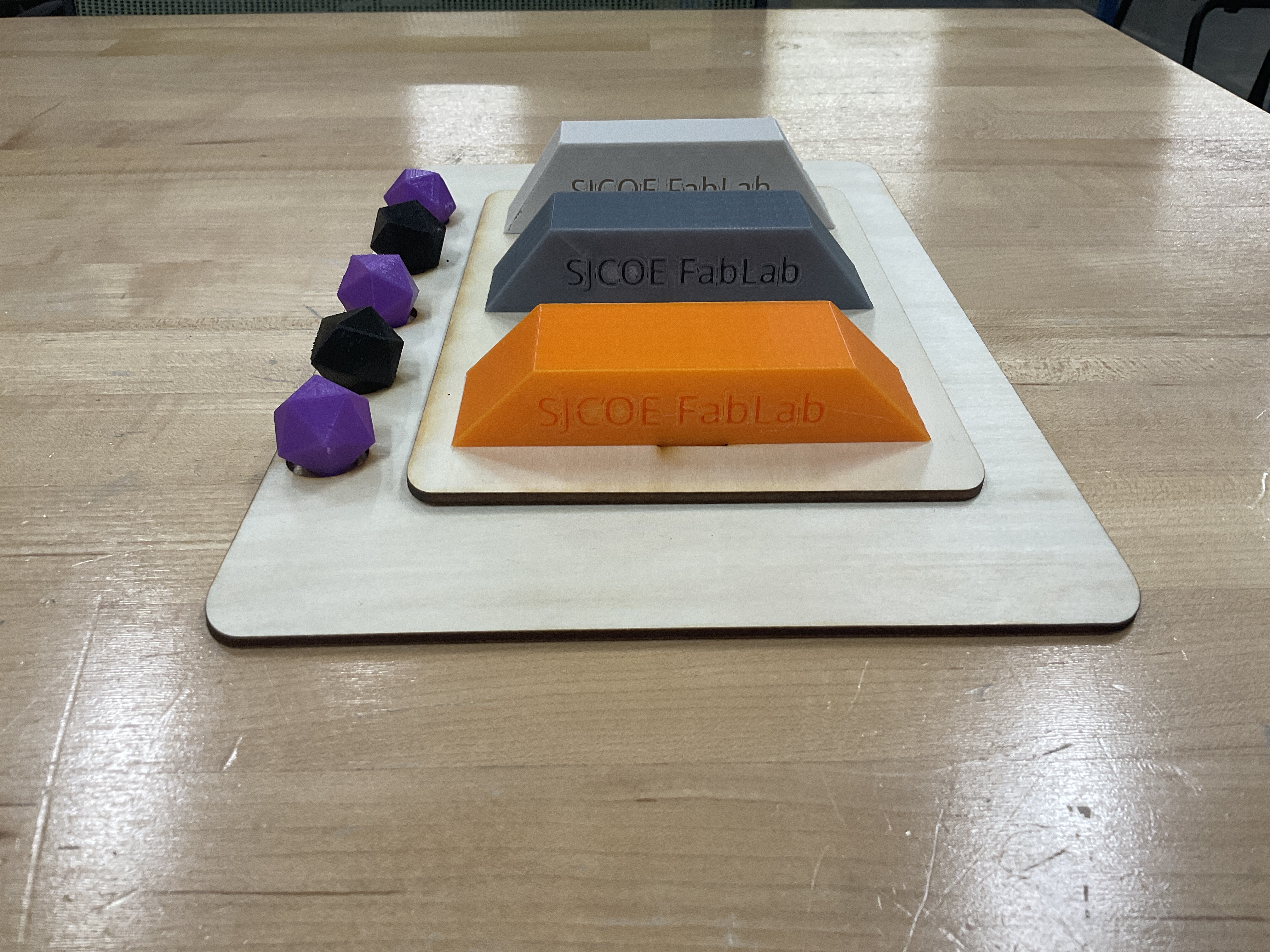 The RoboLab 2026 arena is shown, there are 3 3D printed platforms ontop of a two layer laser-cut wooden base.